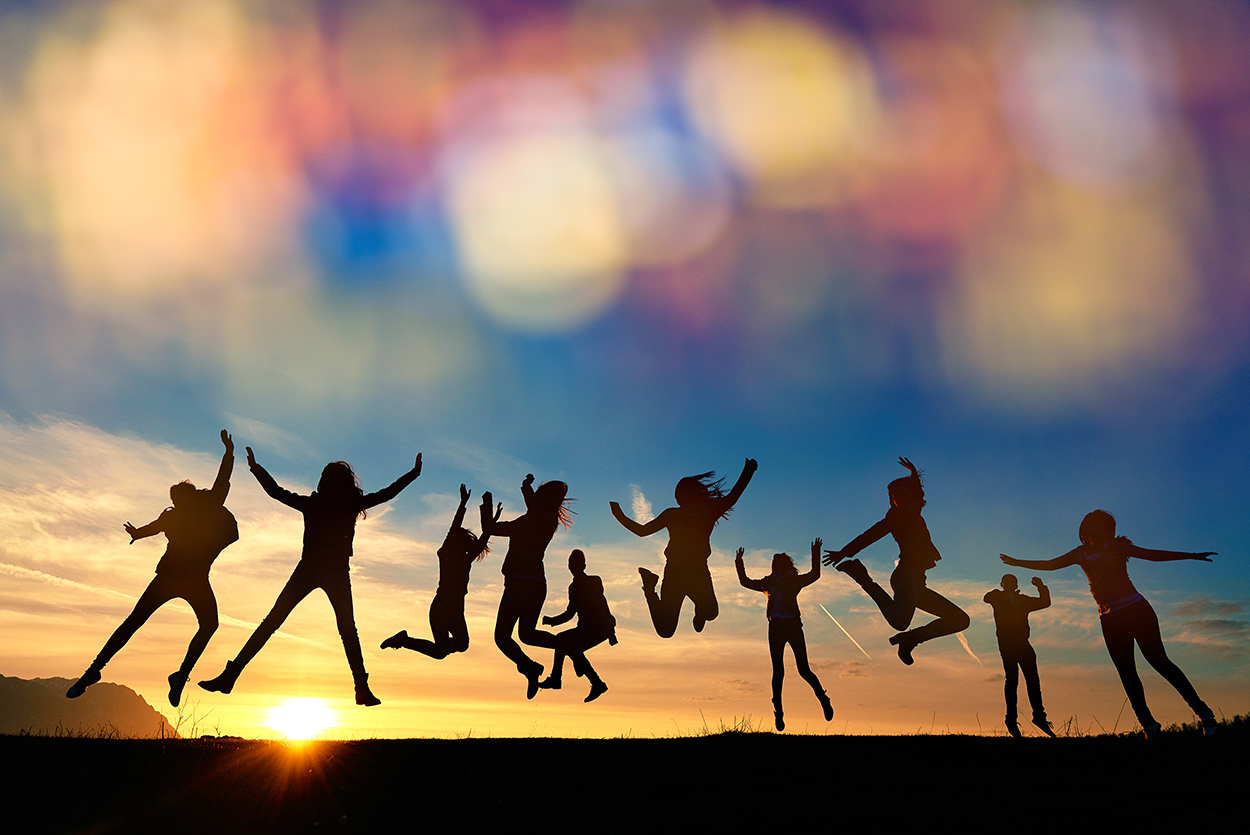 medium group of people feeling energic and carefree, jumping at sunset, defocused lights.silhouettes.