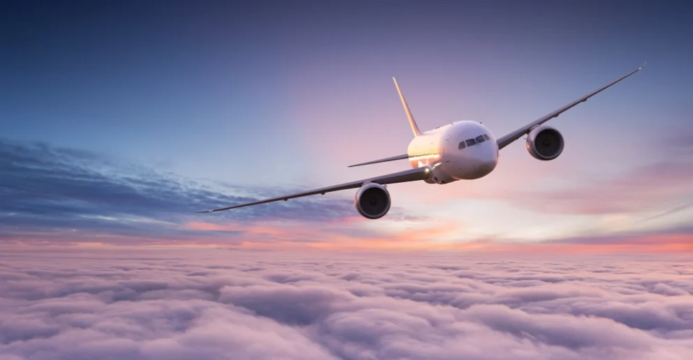 commercial airplane jetliner flying above dramatic clouds in beautiful sunset pink and blue light sky