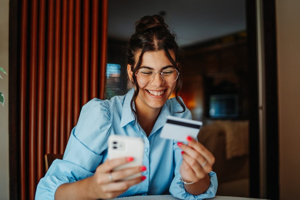 one young women buying an item of her phone looking at her bank card